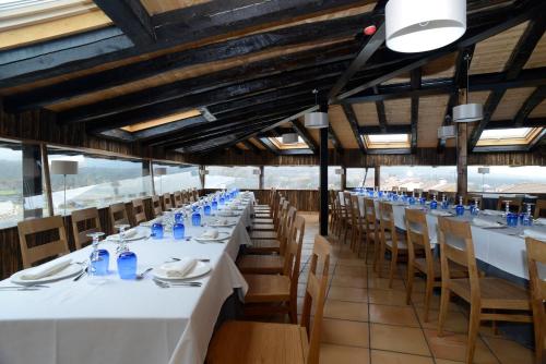 a long dining room with white tables and chairs at Hotel Rural Quercus Tierra in Garganta de los Montes