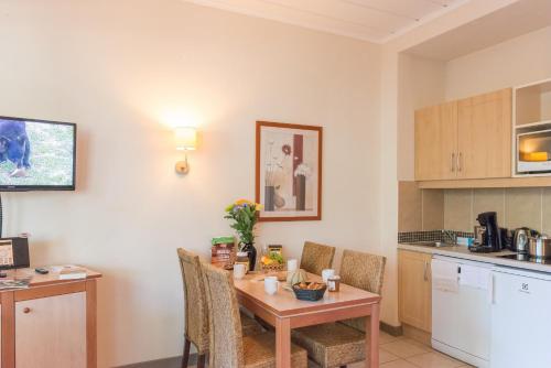 a kitchen with a table and chairs in a kitchen at SOWELL Family Le Vallon in Grospierres