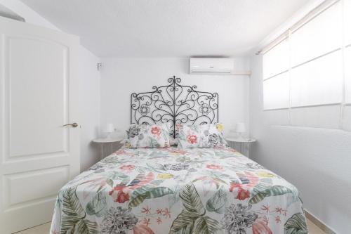 a white bedroom with a bed with a floral bedspread at Casa Vistas Axarquia in Vélez-Málaga