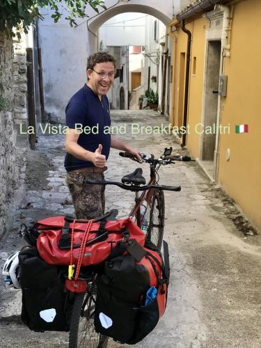 a man standing next to a bike with bags at La Vista in Calitri