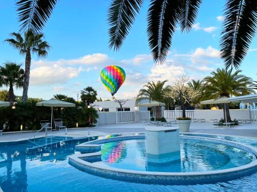 a hot air balloon flying over a swimming pool at UNA HOTELS MH Matera in Matera