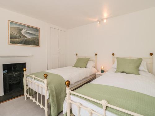 two beds in a room with a fireplace at Overton Cottage in Sturminster Newton