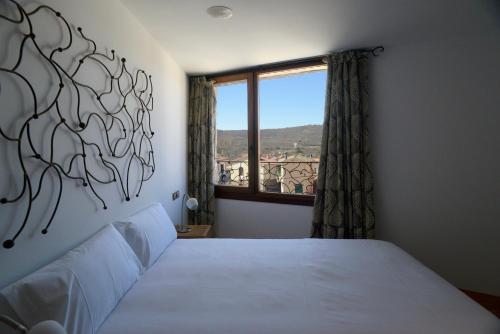 a bedroom with a white bed with a window at Hotel Rural Quercus Tierra in Garganta de los Montes