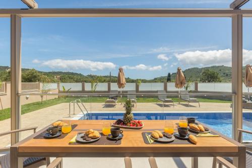 a table with food on it with a view of a pool at Amelia Residence in Tragaki