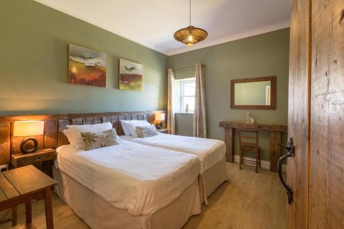 a bedroom with a large bed with white sheets at The Old Cowshed in Kidwelly