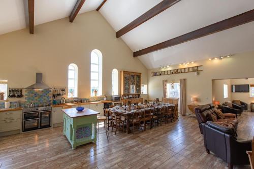 a large kitchen and living room with a dining table at The Old Cowshed in Kidwelly