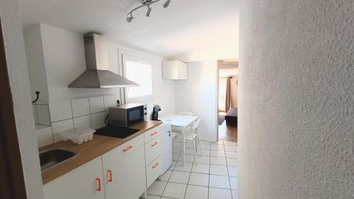 une cuisine blanche avec un évier et un micro-ondes dans l'établissement Narbonne Studio renové centre ville, à Narbonne