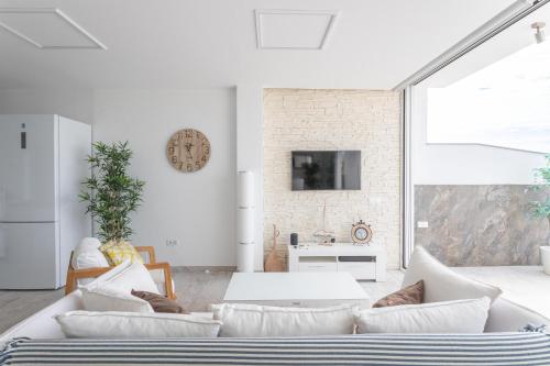 Nerja Luxury Apartment في نيرخا: غرفة معيشة بأثاث أبيض وجدار من الطوب