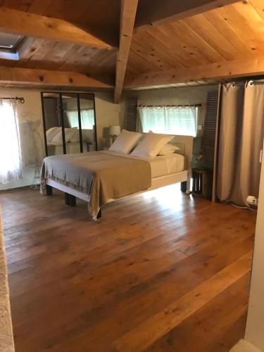 ein Schlafzimmer mit einem Bett in einem Zimmer mit Holzböden in der Unterkunft La Charmeuse in Céreste