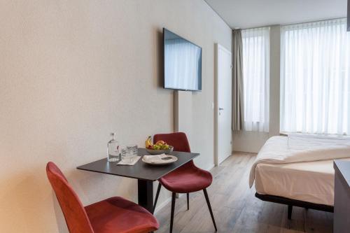 a room with a table and chairs and a bed at Centurion Swiss Quality Towerhotel Windisch in Brugg