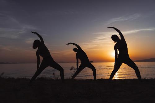 a group of people doing yoga on the beach at Koukoumi Vegan Boutique Hotel in Ano Mera