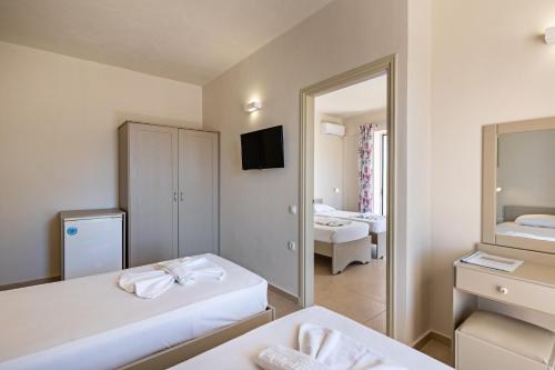 a hotel room with two beds and a mirror at Hotel Kathrin Beach in Adelianos Kampos