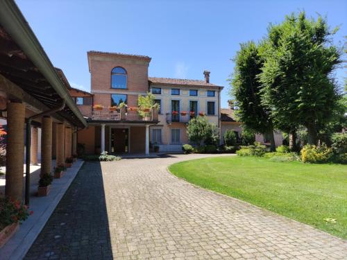 a house with a brick driveway in front of a yard at B&B Villa Valchero in Carpaneto Piacentino