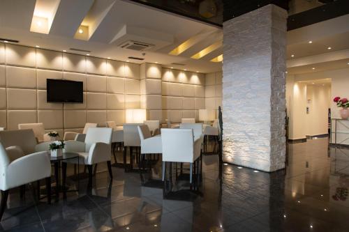 a dining room with white tables and chairs and a tv at Hotel Antico Borgo in Riva del Garda