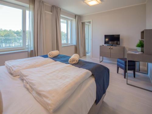een slaapkamer met een bed, een bureau en een televisie bij Dünenresidenz Prora - Ferienwohnung mit Meerblick, 2 Schlafzimmern und Balkon NP-304 in Binz