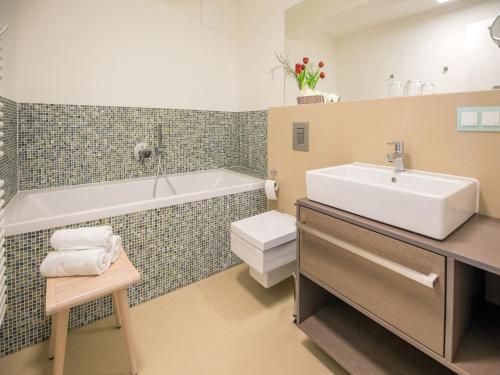 een badkamer met een wastafel, een bad en een toilet bij Dünenresidenz Prora - Ferienwohnung mit Meerblick, 2 Schlafzimmern und Balkon NP-304 in Binz