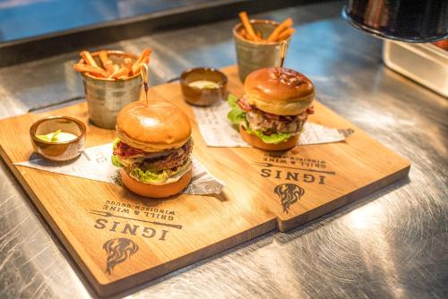 two hamburgers and french fries on a wooden tray at Centurion Swiss Quality Towerhotel Windisch in Brugg