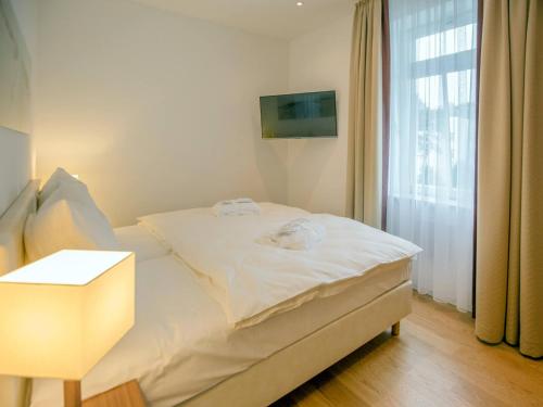 ein weißes Bett in einem Zimmer mit Fenster in der Unterkunft Strandvillen Binz - Appartement mit 1 Schlafzimmer und Balkon SV-004 in Binz