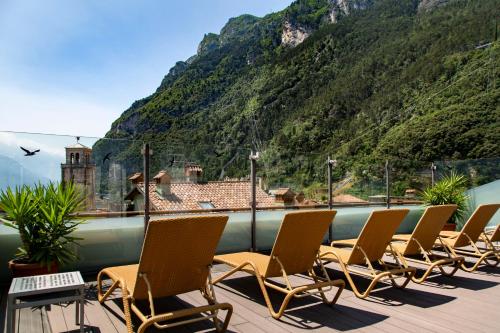eine Reihe von Stühlen auf einer Terrasse mit einem Berg in der Unterkunft Hotel Antico Borgo in Riva del Garda
