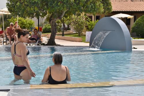 two people in a swimming pool with a fountain at Kikki Village in Modica