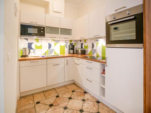 a kitchen with white cabinets and green and white wallpaper at Strandvillen Binz - Ferienwohnung mit Meerblick und 1 Schlafzimmer SV-705 in Binz