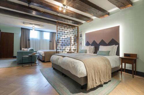 - une chambre avec un grand lit et un salon dans l'établissement The Hendrick's Hotel, à Amsterdam