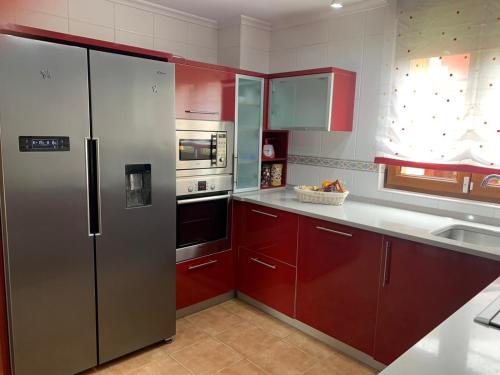 Vargas的住宿－Chalet Individual en Vargas, Cantabria，厨房配有红色橱柜和不锈钢冰箱