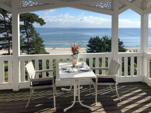 a white porch with a table and chairs and the ocean at Strandvillen Binz - Ferienwohnung mit Meerblick, 1 Schlafzimmer und Balkon SV-762 in Binz