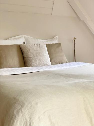 a white bed with white sheets and pillows at Zilt7 in Callantsoog