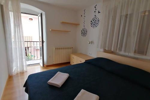 a bedroom with a blue bed and a large window at Apartment Veli Dvor in Cres