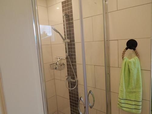 y baño con ducha y toalla verde. en Theunis Ferienwohnung, en Ostseebad Karlshagen