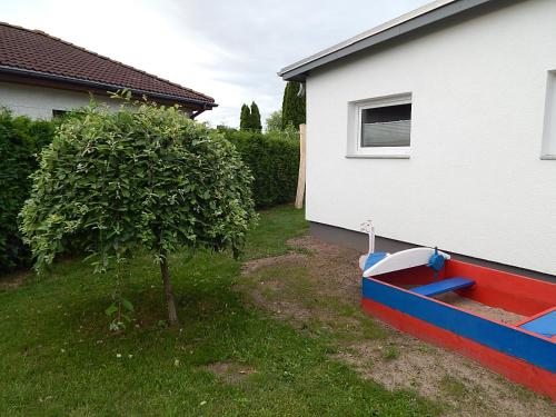 un pequeño árbol en un patio al lado de una casa en Theunis Ferienwohnung, en Ostseebad Karlshagen