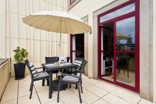 ein Tisch mit Stühlen und einem Sonnenschirm auf einer Terrasse in der Unterkunft Porto Terrace Apartment in Porto