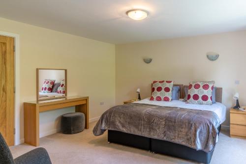 a bedroom with a bed and a table and a mirror at Hill View Rise in Chipping Campden
