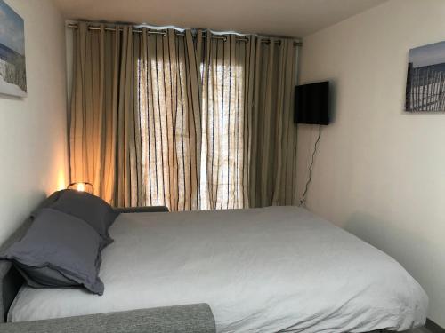 un lit dans une chambre avec une grande fenêtre dans l'établissement Studio à 50 m de la mer avec parking privatif, à Saint-Hilaire-de-Riez