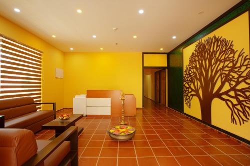 a living room with a couch and a tree mural at Au Revoir Wellness Resort, Malampuzha in Palakkad