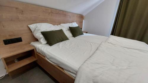 1 cama con sábanas blancas y almohadas verdes en una habitación en Apartmány Jura, en Nová Pec