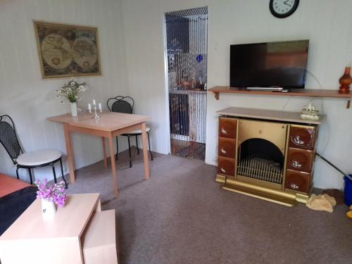 een woonkamer met een open haard, een tafel en een tv bij Bungalow am Waldbad in Schmannewitz