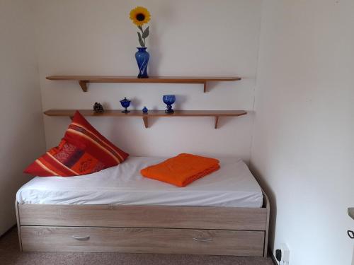 Un dormitorio con una cama con un jarrón en un estante en Bungalow am Waldbad en Schmannewitz
