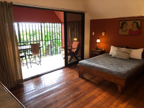 - une chambre avec un lit et une grande porte coulissante en verre dans l'établissement Cockatoo Studio Apartments, à Manuel Antonio