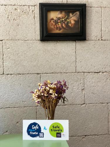a vase of flowers on a table next to a wall at Apartment Lara in Zaton