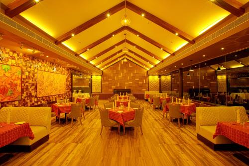 a restaurant with tables and chairs in a room at Au Revoir Wellness Resort, Malampuzha in Palakkad