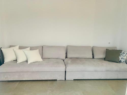 a gray couch with pillows sitting in a living room at Gerani Deluxe Houses 2 in Astypalaia Town