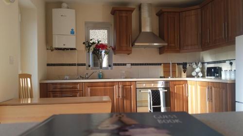 a kitchen with wooden cabinets and a vase of flowers at No2 Glan Nodwydd in Pentraeth