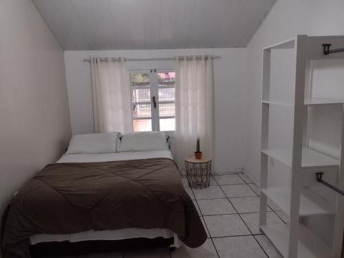 a bed in a white room with a window at Casa de Férias in Florianópolis