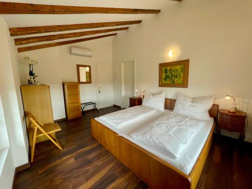1 dormitorio con 1 cama con sábanas blancas y suelo de madera en Casa Bea, en Casa Rougna