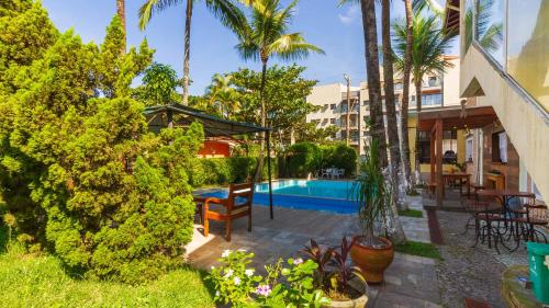 a patio with a table and chairs and a swimming pool at Guarujá Hostel in Guarujá