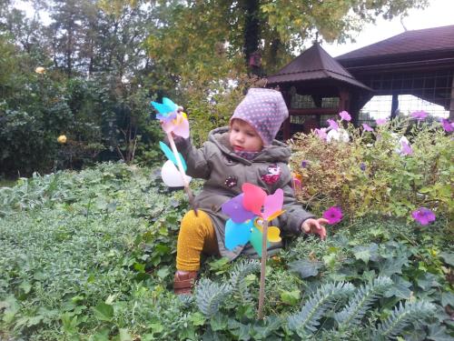 a baby sitting in a garden with a pinwheel at Doppelzimmer im Spreewald in Burg