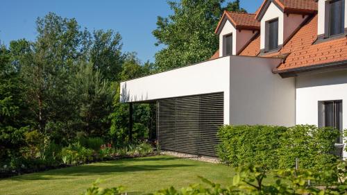 a white house with a garage in a yard at HOTEL Hraniční zámeček in Hlohovec