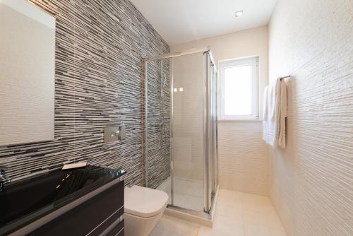 a bathroom with a toilet and a glass shower at Porto de Mós 72 by Destination Algarve in Porto de Mós